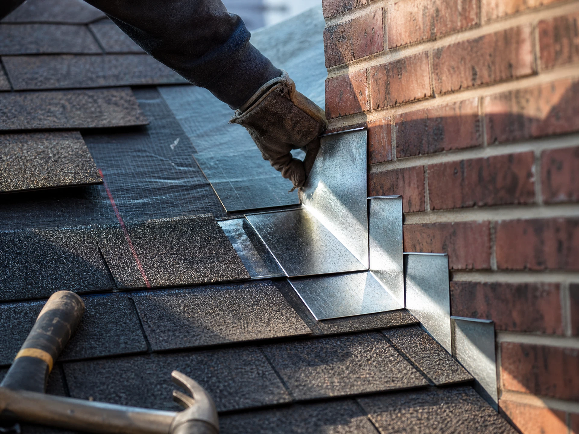New step flashing woven under the shingle course at a chimney. Replaced, not resealed.